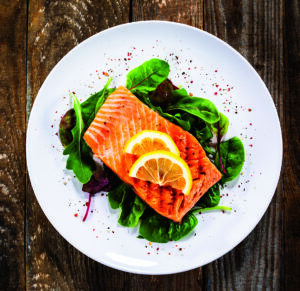 Grilled salmon on fresh vegetables on wooden table